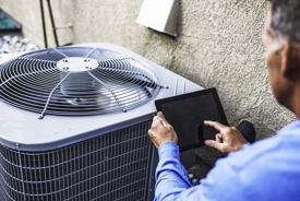 HVAC technician using iPad in front of a new air conditioner. 